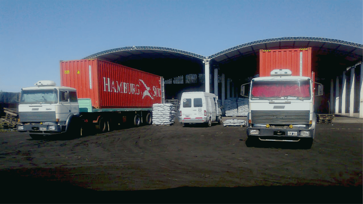 Operaciones logísticas en depósito con camiones y contenedores.